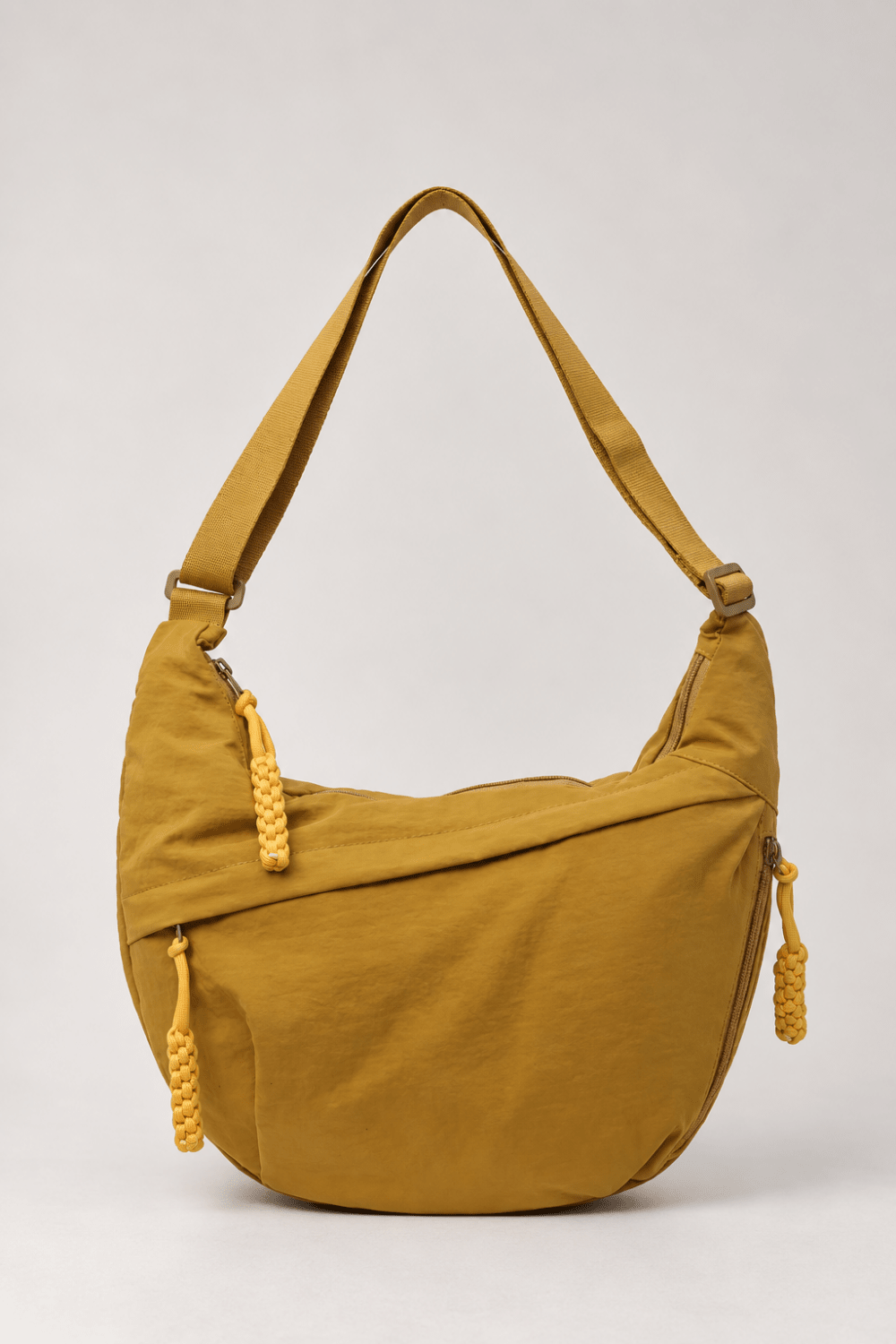 Bolso bandolera de nylon en forma de media luna en color amarillo mostaza, de la marca Vera Serrat, con detalles visibles.
