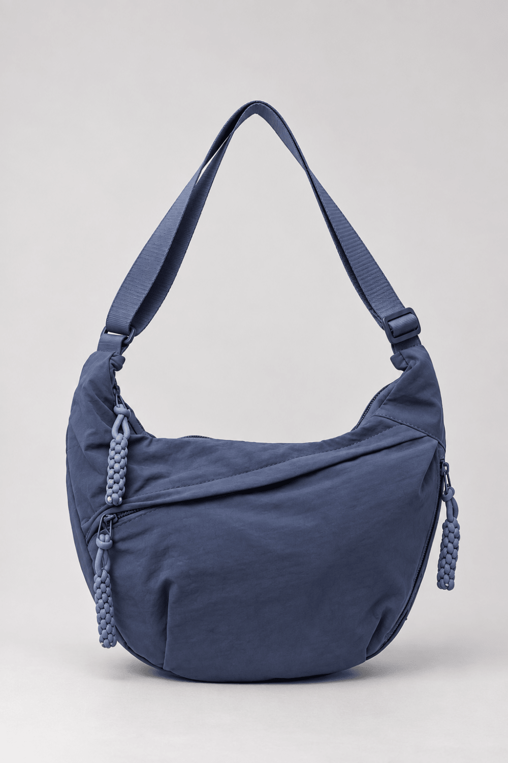Bolso bandolera de nylon con diseño media luna en color azul marino, de la marca Vera Serrat, sobre fondo neutro.