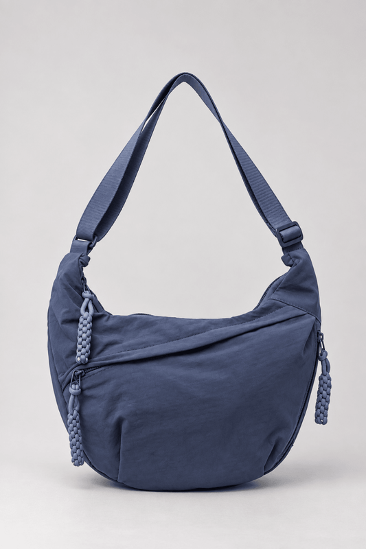 Bolso bandolera de nylon con diseño media luna en color azul marino, de la marca Vera Serrat, sobre fondo neutro.