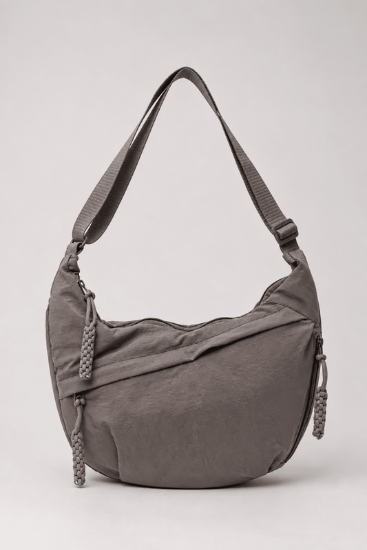 Bolso bandolera de nylon gris con diseño media luna de Vera Serrat, con correa ajustable y detalles elegantes.