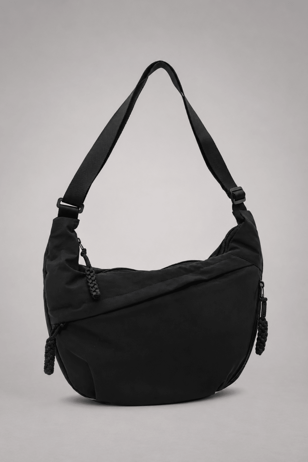 Bolso bandolera de nylon negro con diseño media luna de la marca Vera Serrat, con correa ajustable y detalles elegantes.