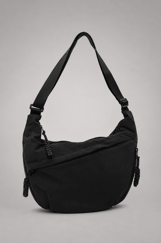 Bolso bandolera de nylon negro con diseño media luna de la marca Vera Serrat, con correa ajustable y detalles elegantes.