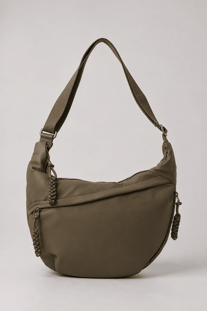 Bolso bandolera de nylon Vera Serrat con diseño media luna en color verde oliva, mostrando detalles y correa ajustable.